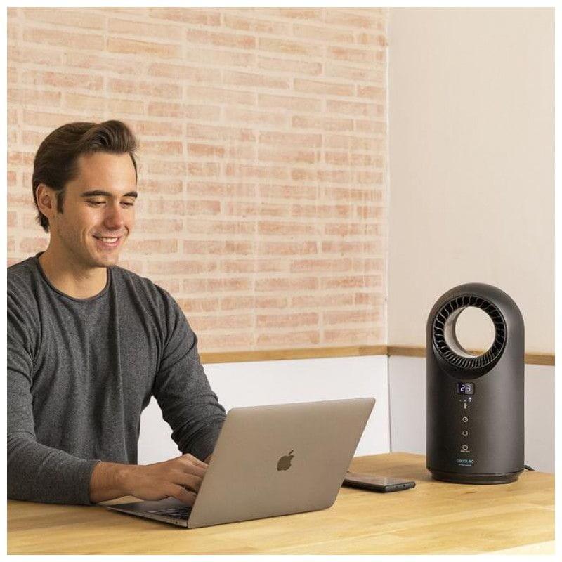 Jovem com seu computador enquanto utiliza seu aquecedor Cecotec ReadyWarm 8400 Bladeless 1500 preto