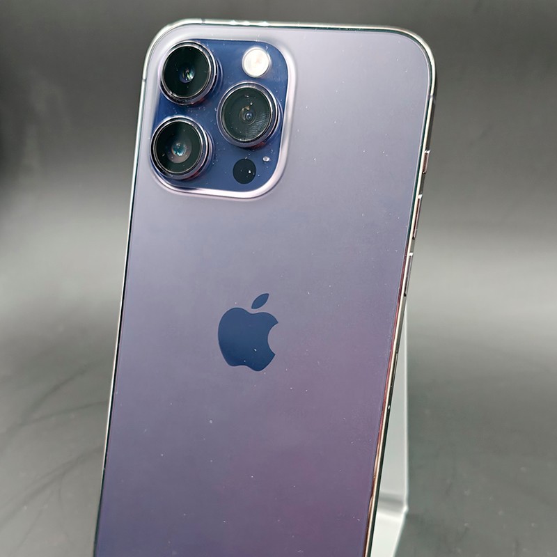 iPhone 14 Pro Max morado oscuro, acabado brillante, triple cámara trasera con lentes grandes, bordes metálicos pulidos; aspecto renovado en excelente estado.