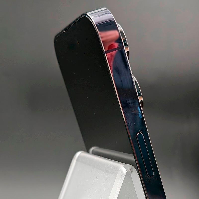 Lateral del iPhone 14 Pro Max morado oscuro, borde brillante con acabado espejo y botones alineados; cámara trasera doble sobresaliente, estado excelente.