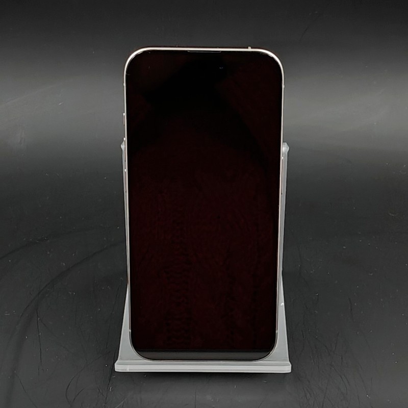 Écran noir bord à bord, bords fins en titane naturel, format rectangulaire. Appareil posé sur support gris, façade sans boutons visibles.