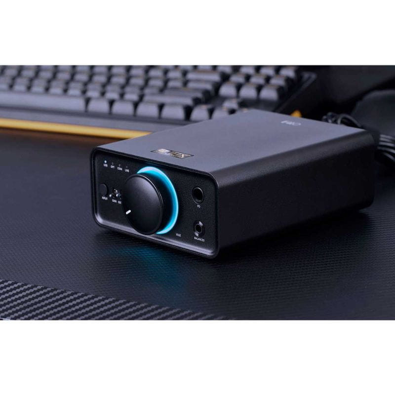 FiiO K7 Negro - Amplificador/DAC compacto con perilla iluminada azul, indicador de ganancia, salidas para auriculares y chasis metálico sobre escritorio