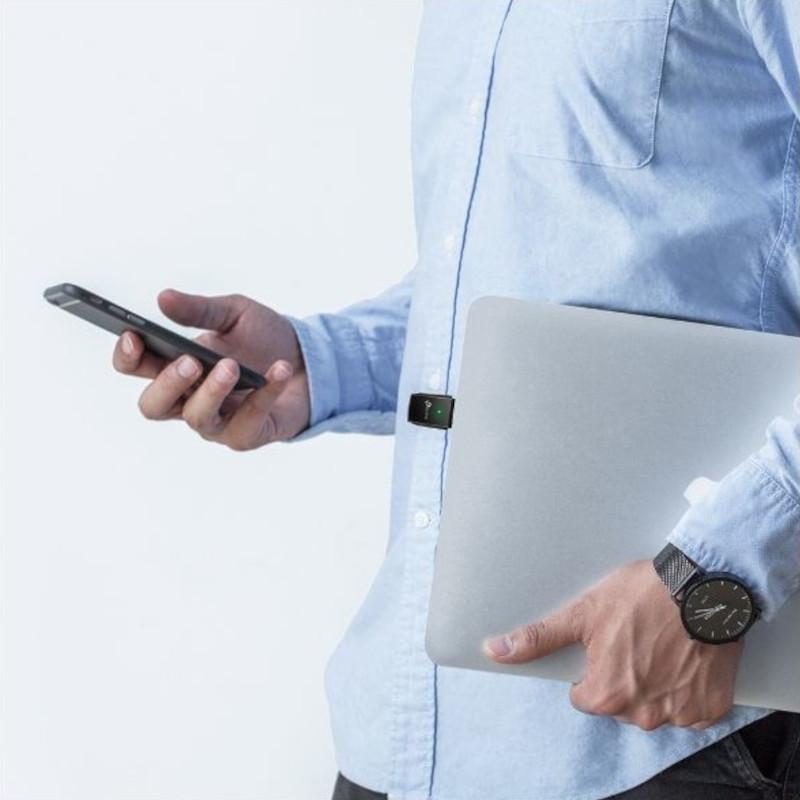 Adaptador USB TP-Link Archer T2U AC600 conectado a laptop, diseño compacto negro con indicador LED verde; usuario sosteniendo móvil y portátil plateada