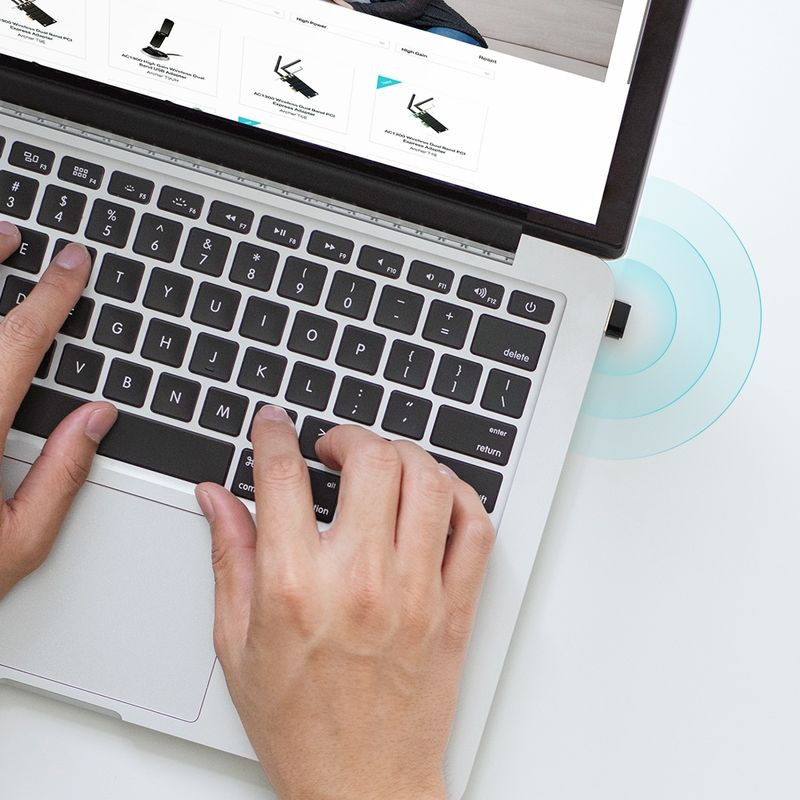 Adaptador WiFi USB TP-Link Archer T600U compacto en negro, conectado a un portátil junto al teclado. Diseño minimalista con indicador LED y perfil discreto.