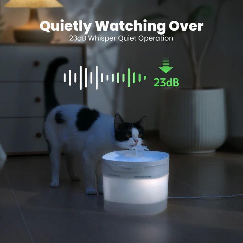 Bebedero automático blanco con luz suave, operación ultrasilenciosa de 23 dB. Gato bebiendo, diseño compacto y translúcido con cable lateral.