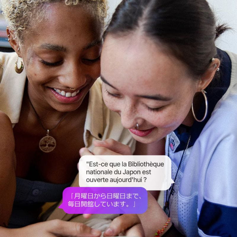 Ikko ActiveBuds AB02 – balão de tradução na tela de smartphone, exibindo frases em francês e japonês enquanto duas pessoas interagem sorrindo.
