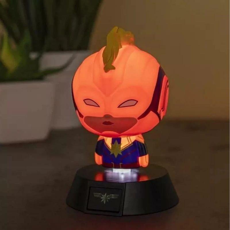 Lámpara Paladone Icon Captain Marvel: mini figura chibi iluminada en tonos cálidos, traje azul con estrella dorada, base negra con emblema brillante.