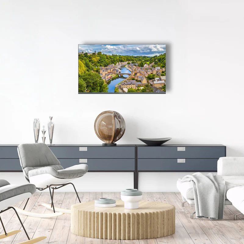 THOMSON 40FQG3S15 40" Smart TV con pantalla plana, marco delgado y colores vivos; montado en pared, muestra paisaje nítido en sala moderna y minimalista.