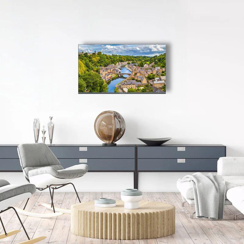 THOMSON 40FQG3S15 40" Smart TV con pantalla plana, marco delgado y colores vivos; montado en pared, muestra paisaje nítido en sala moderna y minimalista.