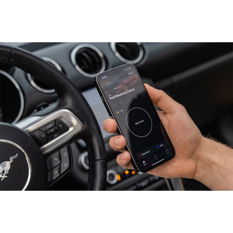Scanner de diagnostic OBDeleven 3 avec app mobile affichée sur smartphone, interface noire, utilisé dans l’habitacle d’une voiture moderne (tableau de