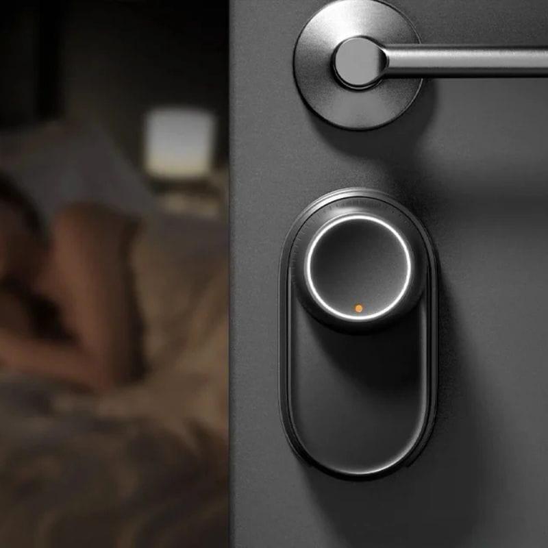 Cerradura inteligente SwitchBot Ultra 3 en 1 en puerta oscura, acabado negro mate, aro LED circular con indicador naranja, diseño minimalista y compacto