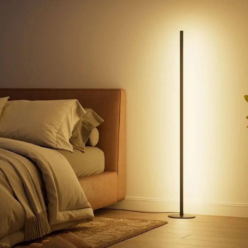 Candeeiro de pé inteligente SwitchBot com corpo cilindrico preto e base circular, luz LED warm indireta iluminando a parede, design minimalista para sala ou