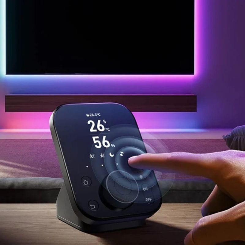 Centralita inteligente SwitchBot Hub 3 con pantalla táctil inclinada, indicadores de temperatura y humedad, iconos retroiluminados y diseño compacto en base