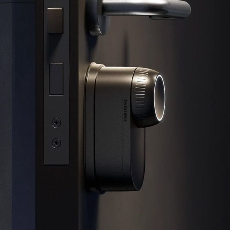 Fecho inteligente SwitchBot Lock Ultra Preto com corpo cilíndrico fosco, aro iluminado e encaixe sob maçaneta; design minimalista para porta de entrada