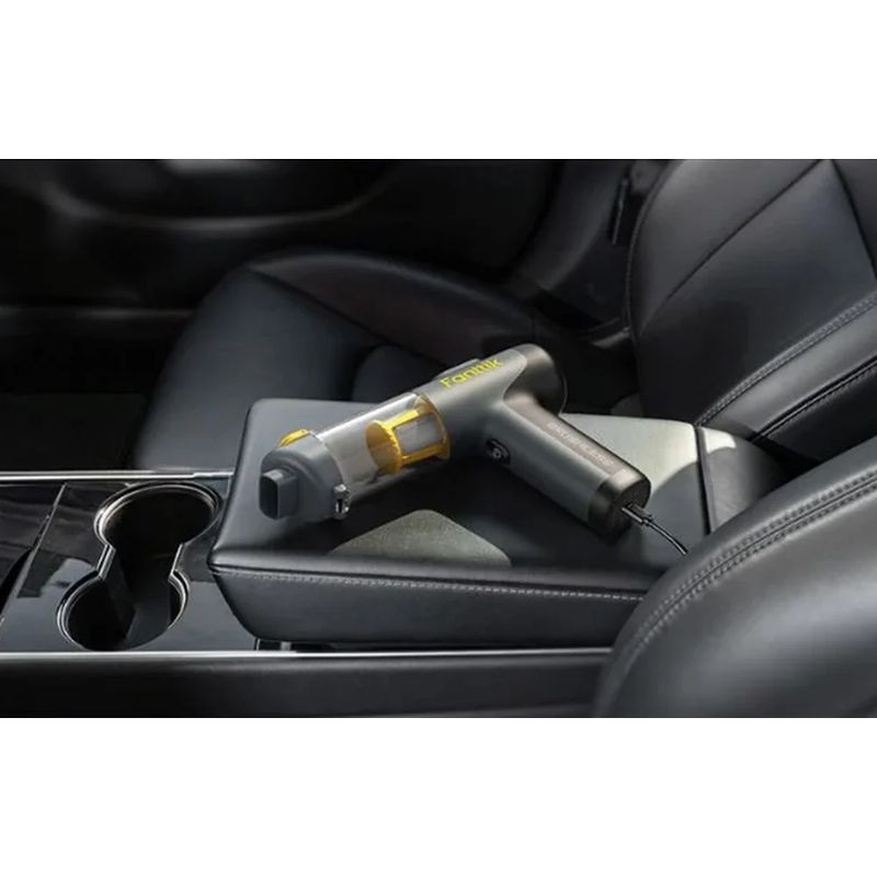 Fanttik Slim V9 Mix aspirateur à main sans fil, compact noir, réservoir transparent jaune, posé sur accoudoir de voiture, câble branché pour recharge