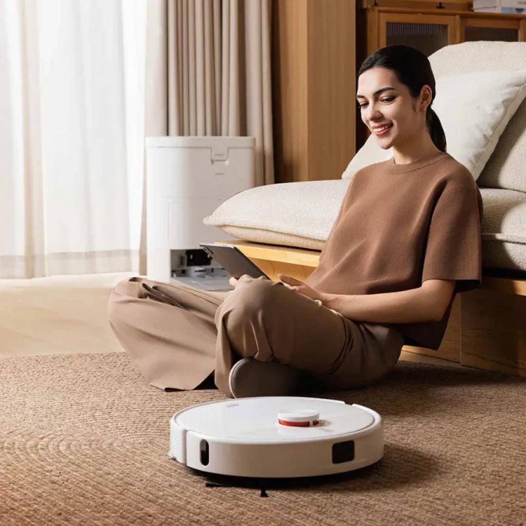 Xiaomi Robot Vacuum H50 blanco con torre de autolimpieza al fondo; diseño circular bajo, sensor láser superior y paragolpes frontal