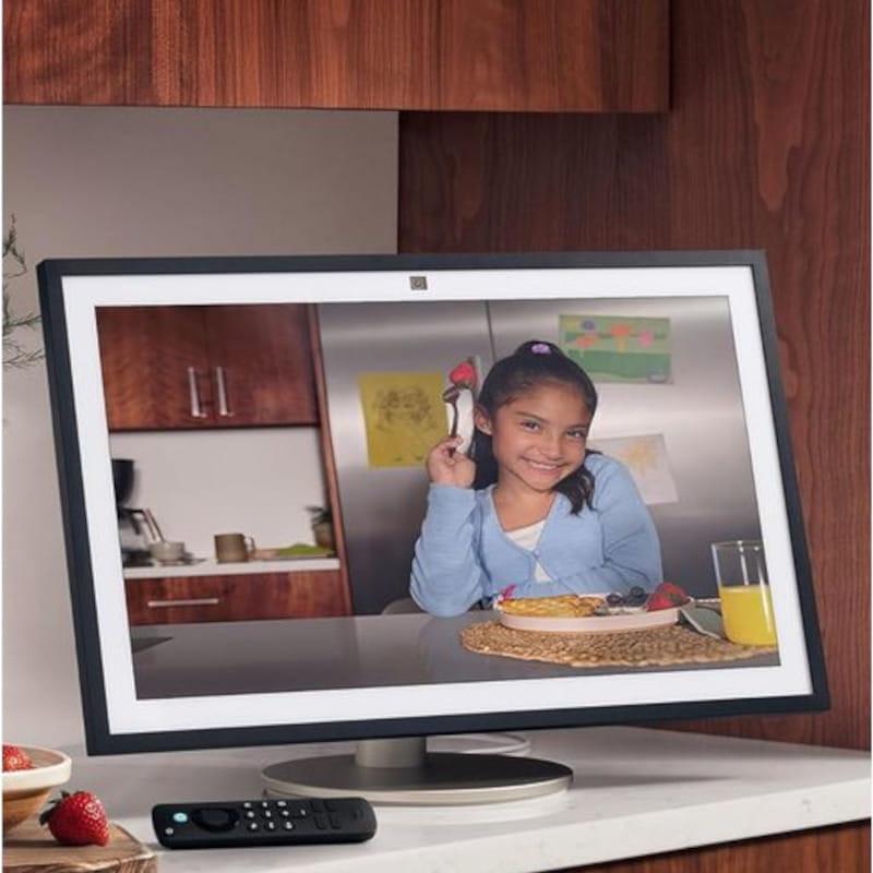 Pantalla inteligente 15.6 pulgadas Full HD con marco negro y bisel blanco, peana metálica, cámara superior central y mando por voz Alexa junto a la base