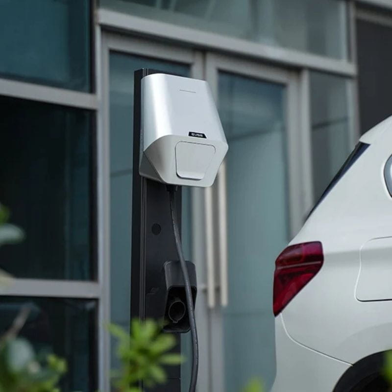Besen LX30 22kW APP Blanco: cargador mural gris/blanco con cable integrado, diseño compacto en poste negro junto a coche, ideal para exteriores