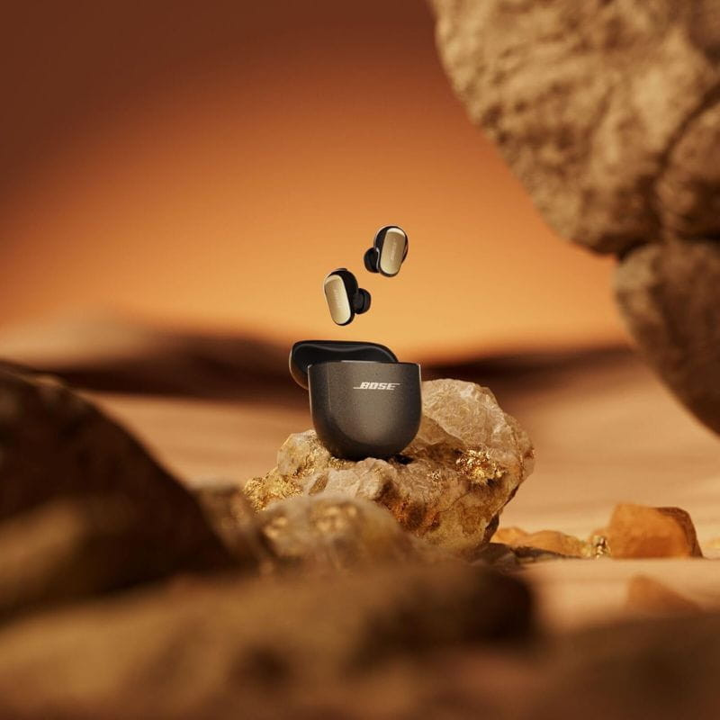 Bose QuietComfort Ultra 2e génération TWS Desert Gold – Écouteurs Bluetooth élégants bicolores avec étui noir, embouts dorés flottant sur décor