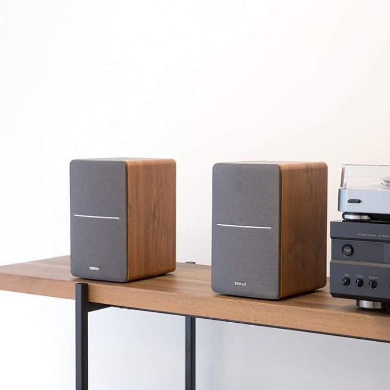 Edifier P12 40W Roble - Altavoces pasivos de madera con frontal gris, diseño minimalista, colocados en pareja sobre mesa junto a equipo de audio