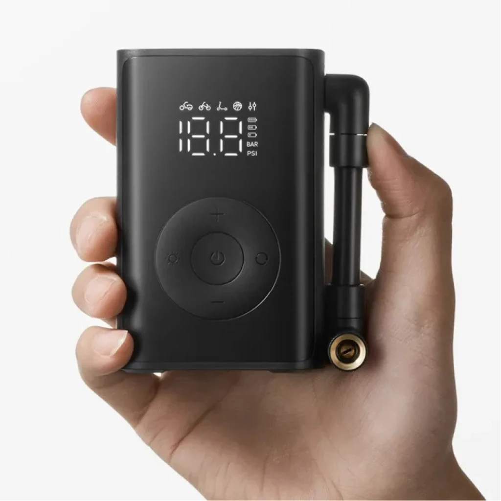 Compresor portátil negro con pantalla LED sostenido por una mano para referencia de tamaño