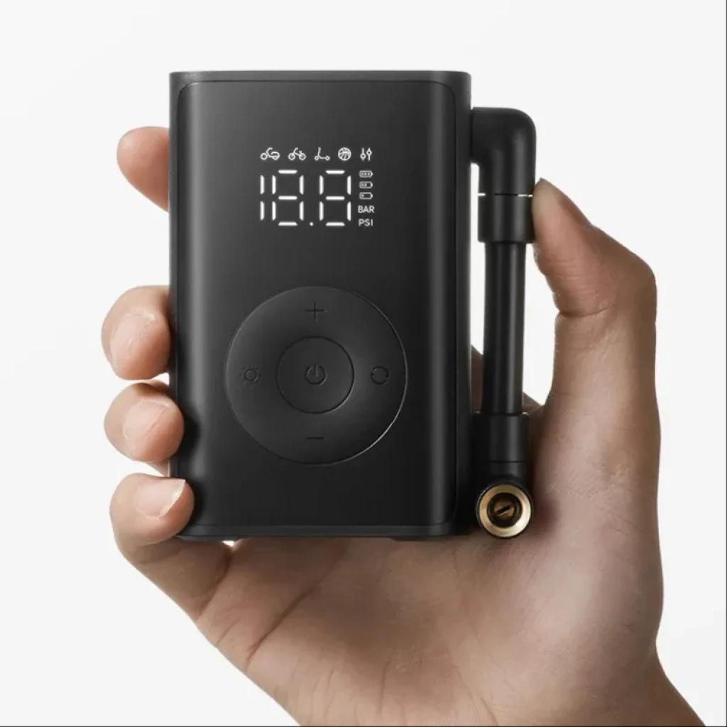 Compresor portátil negro con pantalla LED sostenido por una mano para referencia de tamaño