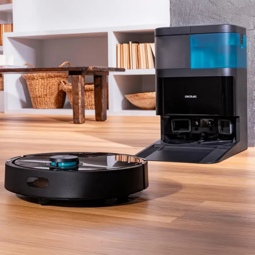 Cecotec Conga 15090 SpinArm robot negro con torreta láser y tapa metálica junto a base de autovaciado negra con depósito azul translúcido en suelo de madera