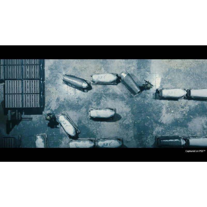 Capture PS5 de Death Stranding Directors Cut : vue aérienne d’un terrain gris, caissons blancs alignés, deux silhouettes en mouvement parmi les obstacles