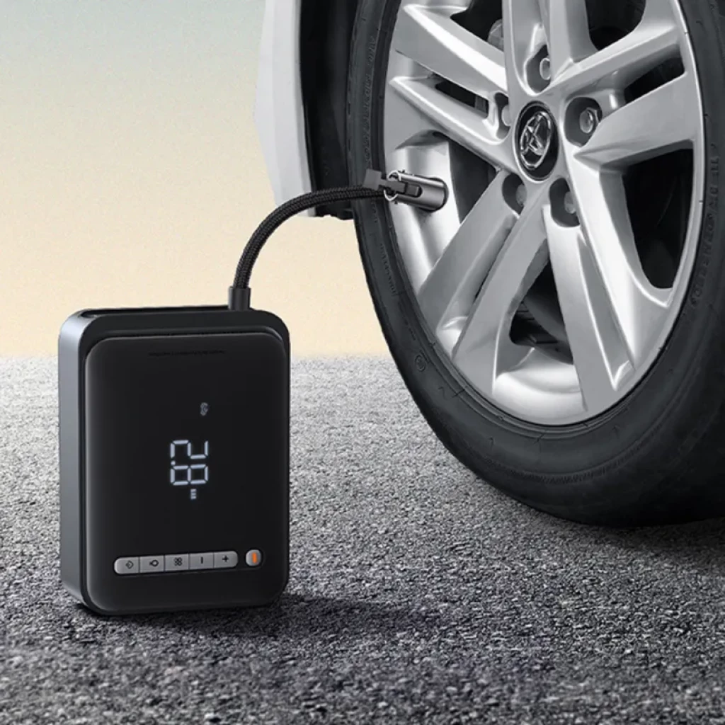 Compresor portátil Baseus con pantalla LED inflando neumático de coche; diseño compacto, manguera flexible y botones frontales junto a indicador luminoso