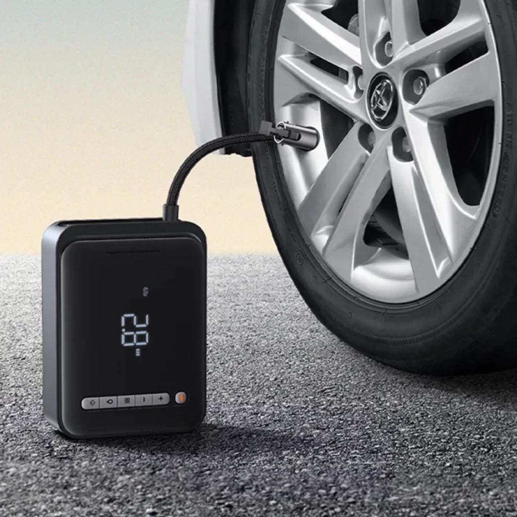 Compresor portátil Baseus con pantalla LED inflando neumático de coche; diseño compacto, manguera flexible y botones frontales junto a indicador luminoso
