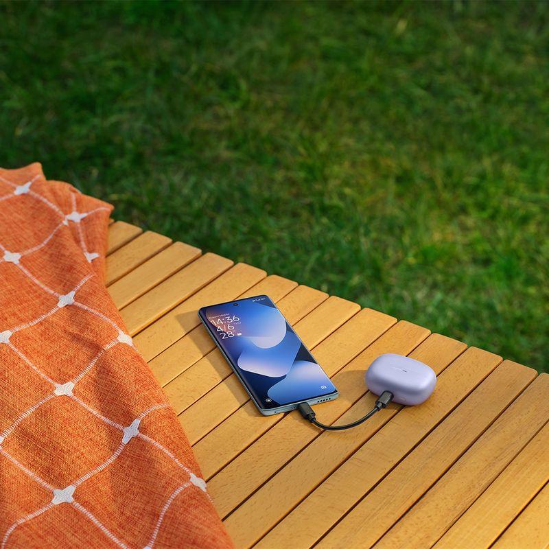 Xiaomi Redmi Note 15 5G púrpura con 8GB/256GB, pantalla amplia de bordes curvos, carga por cable tipo C y estuche de auriculares a juego sobre mesa de madera