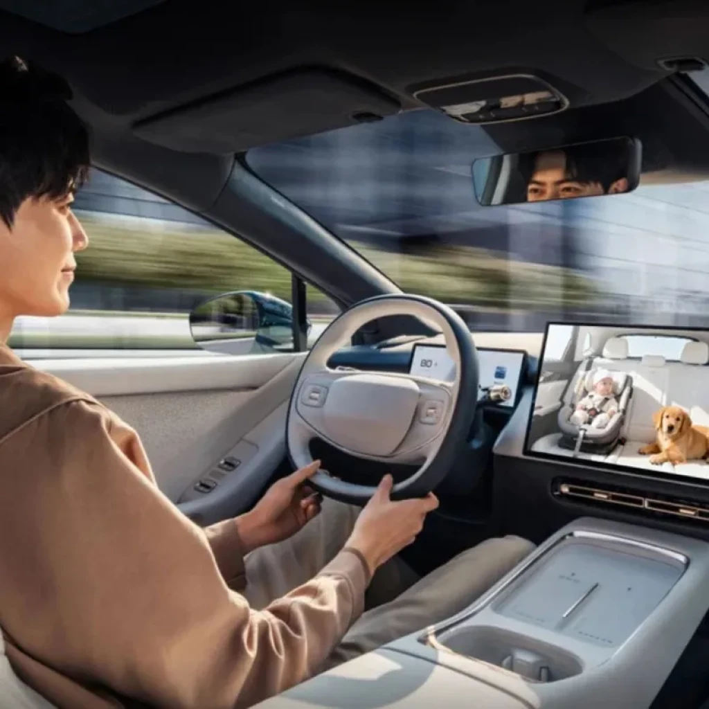 Bebé dormido en silla infantil con arnés en asiento trasero; cámara de Cabina Care monitorea seguridad dentro del coche para uso con adaptador Ottocast