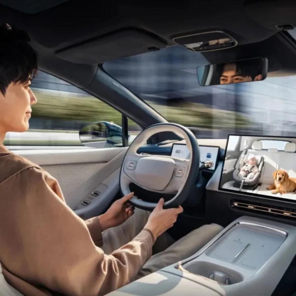 Bebé dormido en silla infantil con arnés en asiento trasero; cámara de Cabina Care monitorea seguridad dentro del coche para uso con adaptador Ottocast