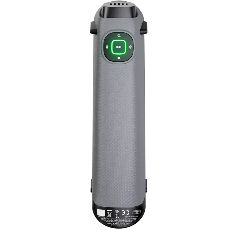 Mando portátil gris con botón verde central y controles táctiles, carcasa texturizada, rejillas de ventilación superiores y base con iconos de