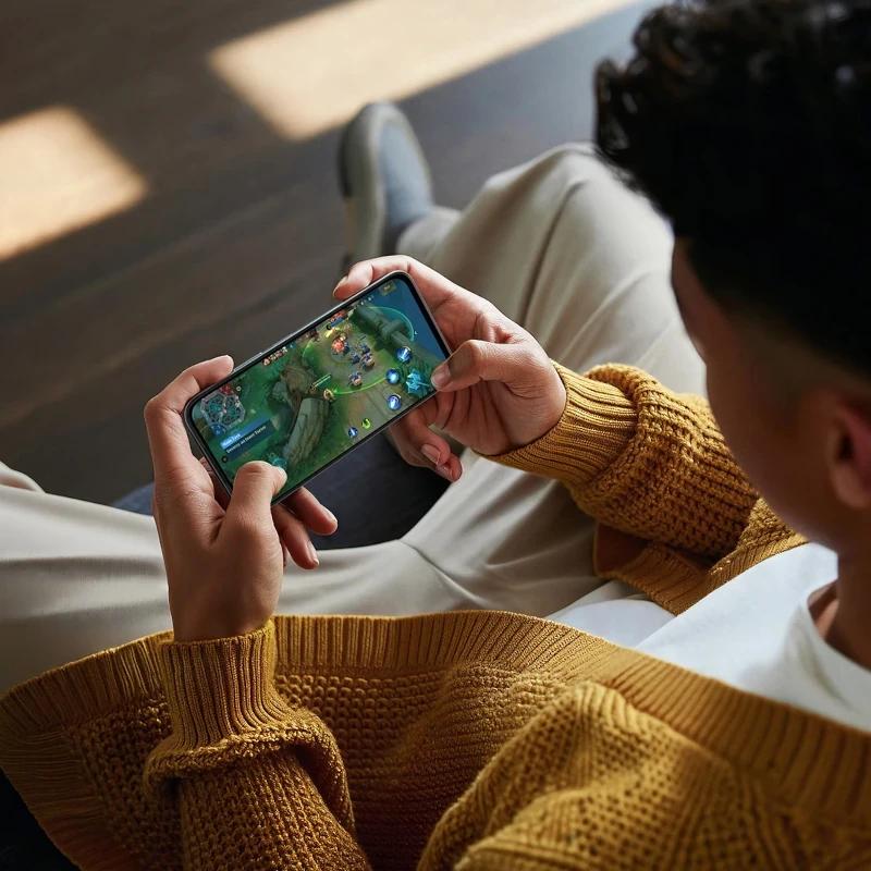 Oppo A6X preto lilás em uso, ecrã 6,75 pol exibindo jogo, bordas finas e corpo elegante; destaca-se pela ergonomia e boa pegada