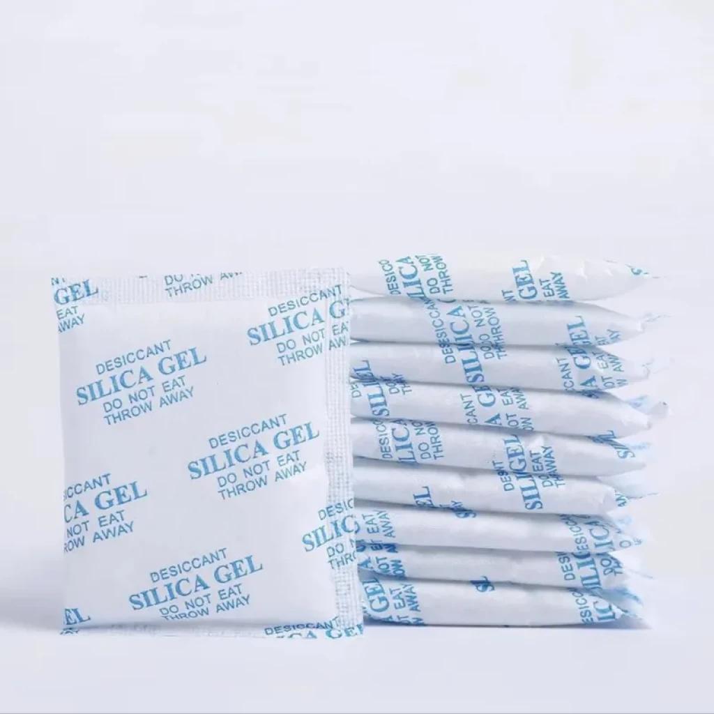 Sobres desecantes de gel de sílice blancos con texto azul, formato individual y pack apilado. Mantienen el pienso seco para comedero inteligente Petkit.