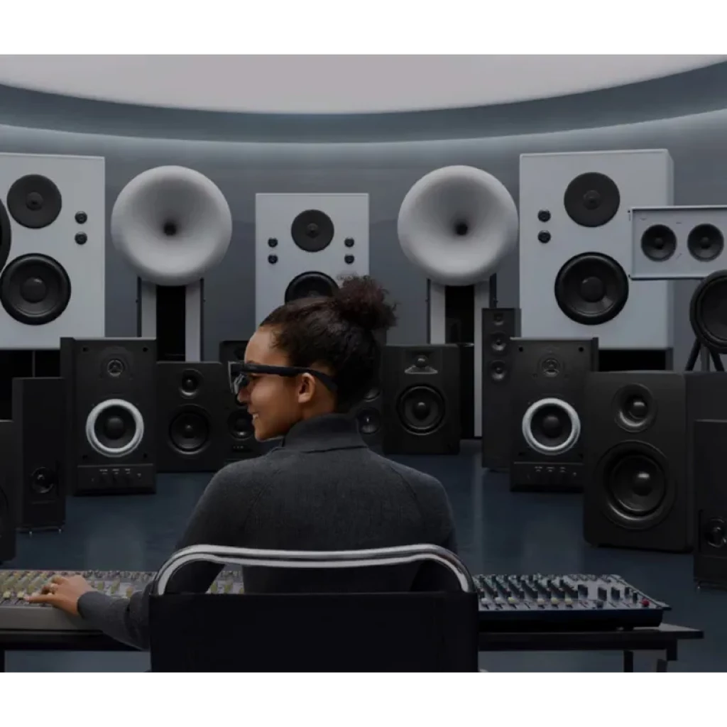 Jeune femme portant AR RayNeo Air 3S Pro eyepiece, lunettes AR noires, monture épaisse et verres fumés, testées en studio audio entouré d’enceintes