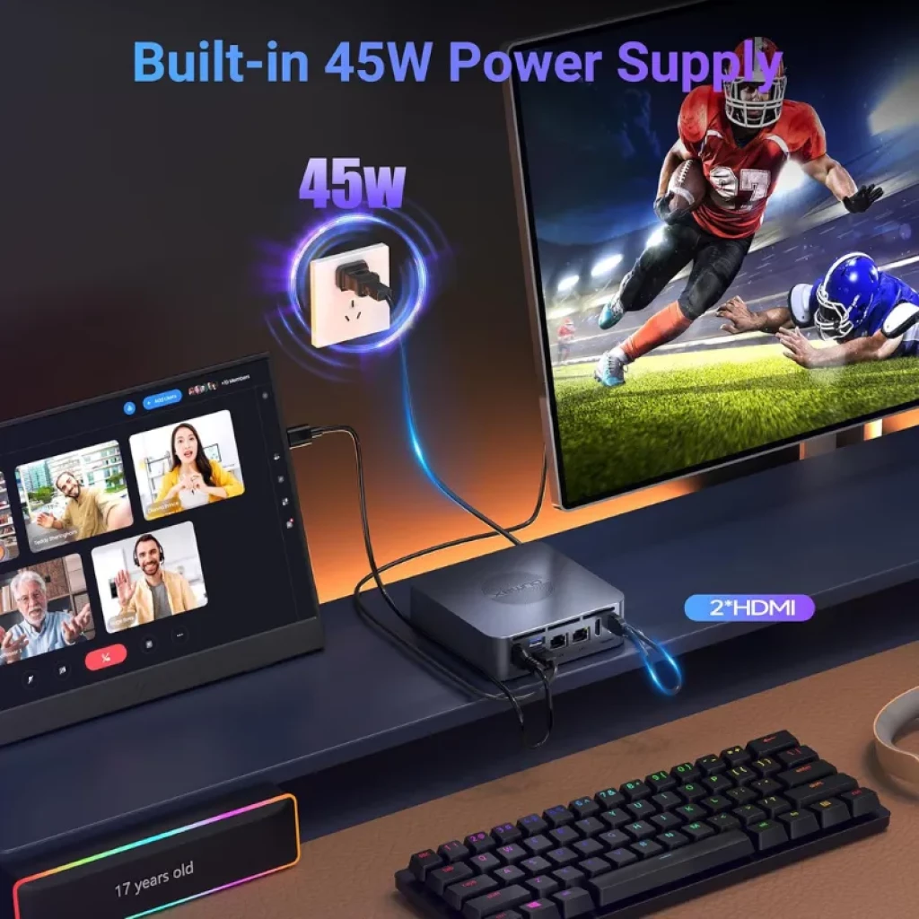 Oumax MAX N100 mini PC gris con fuente integrada 45W, doble HDMI, puertos frontales USB y jack, conectado a monitor y teclado RGB en escritorio gaming