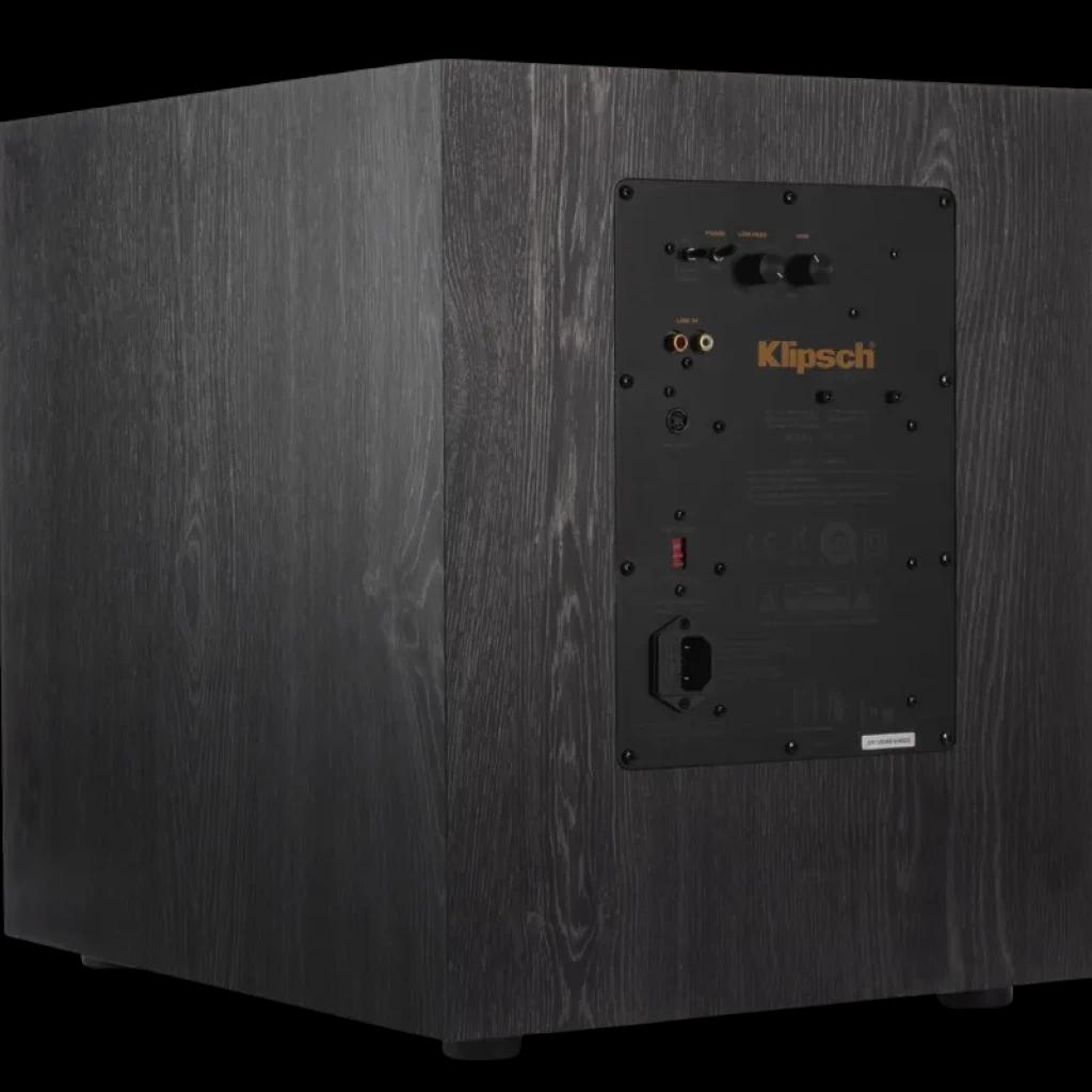 Klipsch SPL 120 CE: gabinete em madeira escura com painel traseiro preto, entradas RCA e LFE, controles de ganho e fase, pés antivibração