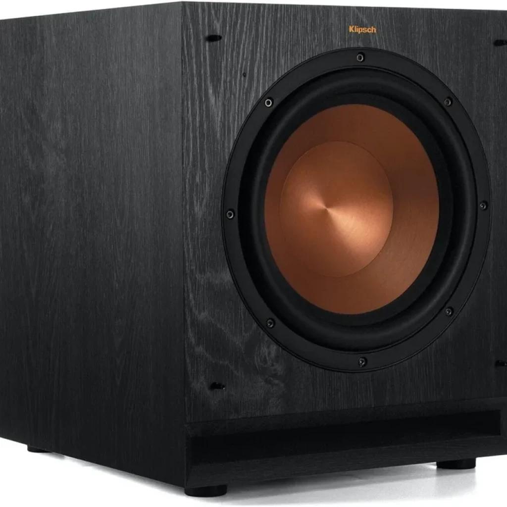 Klipsch SPL 100 CE subwoofer ativo 10 pol, cone cobre, gabinete preto com textura madeira, porta frontal e bordas limpas; design robusto e moderno