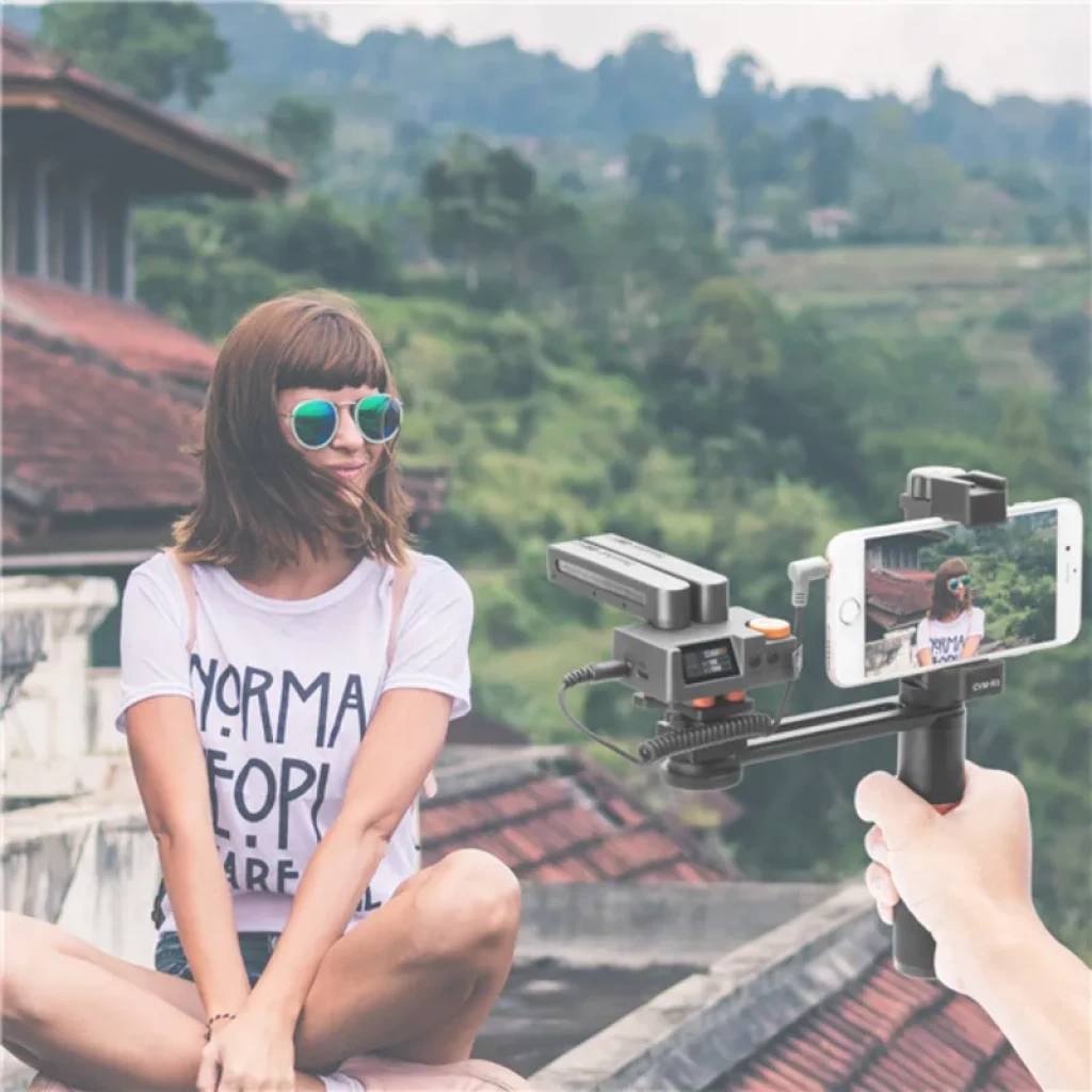 Comica Traxshot Transformável com Ecrã OLED montado em smartphone; microfone shotgun multimodo com módulos ajustáveis, suporte handheld e cabos conectados