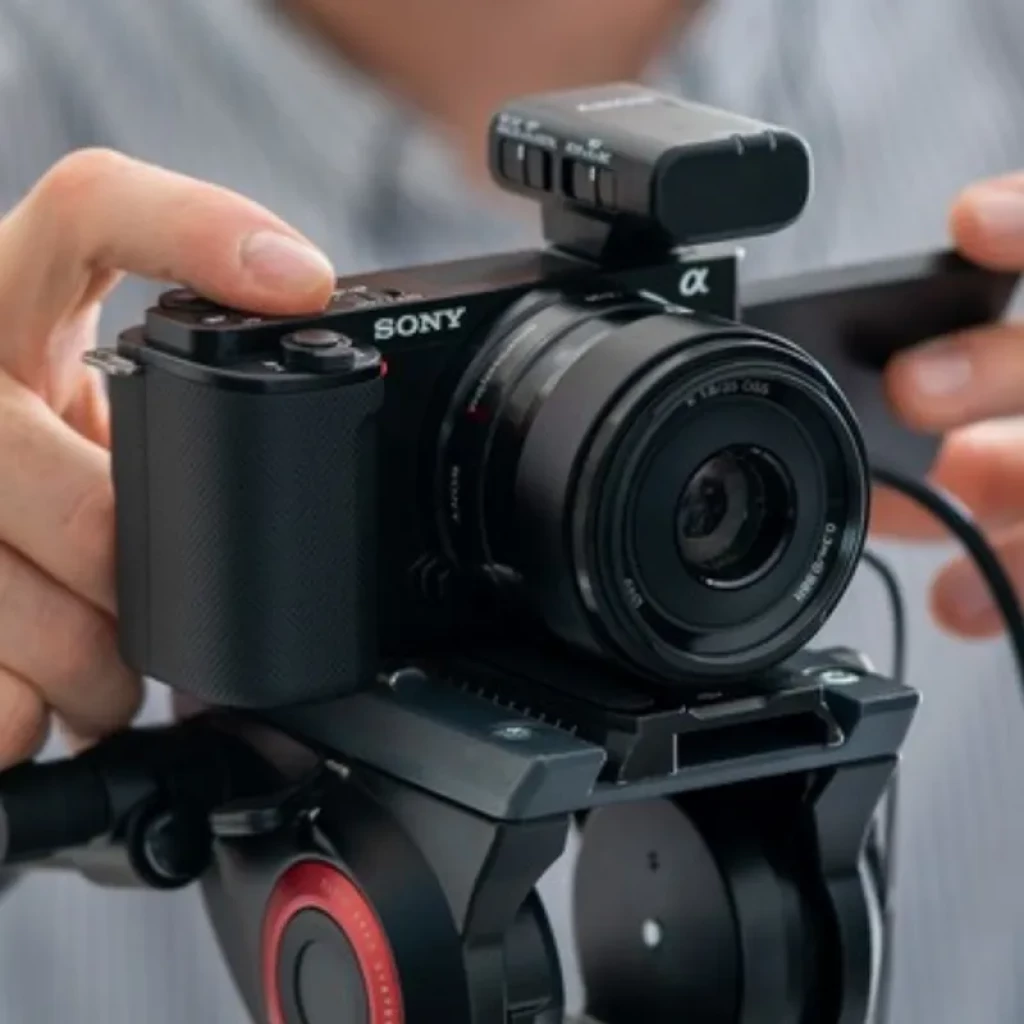 Sony Alpha ZV-E10 con lente intercambiable, pantalla articulada, micro superior y montada en trípode; diseño compacto ideal para vlogging en 4K