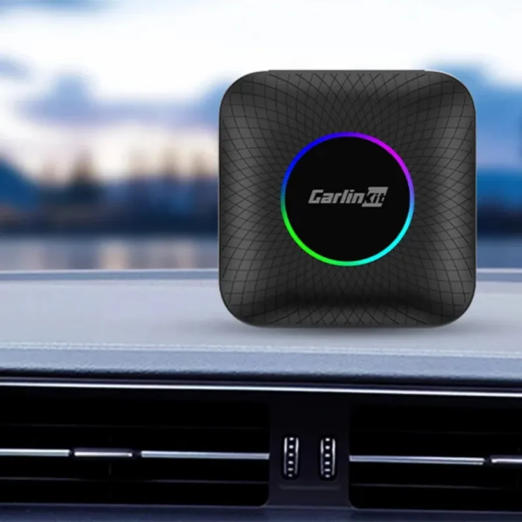 Carlinkit TBOX-Plus compacto, carcasa negra texturizada, logo central con aro LED multicolor, diseño cuadrado de bordes redondeados ideal para salpicadero de