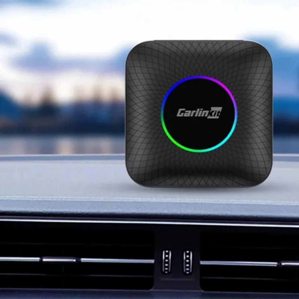 Carlinkit TBOX-Plus compacto, carcasa negra texturizada, logo central con aro LED multicolor, diseño cuadrado de bordes redondeados ideal para salpicadero de