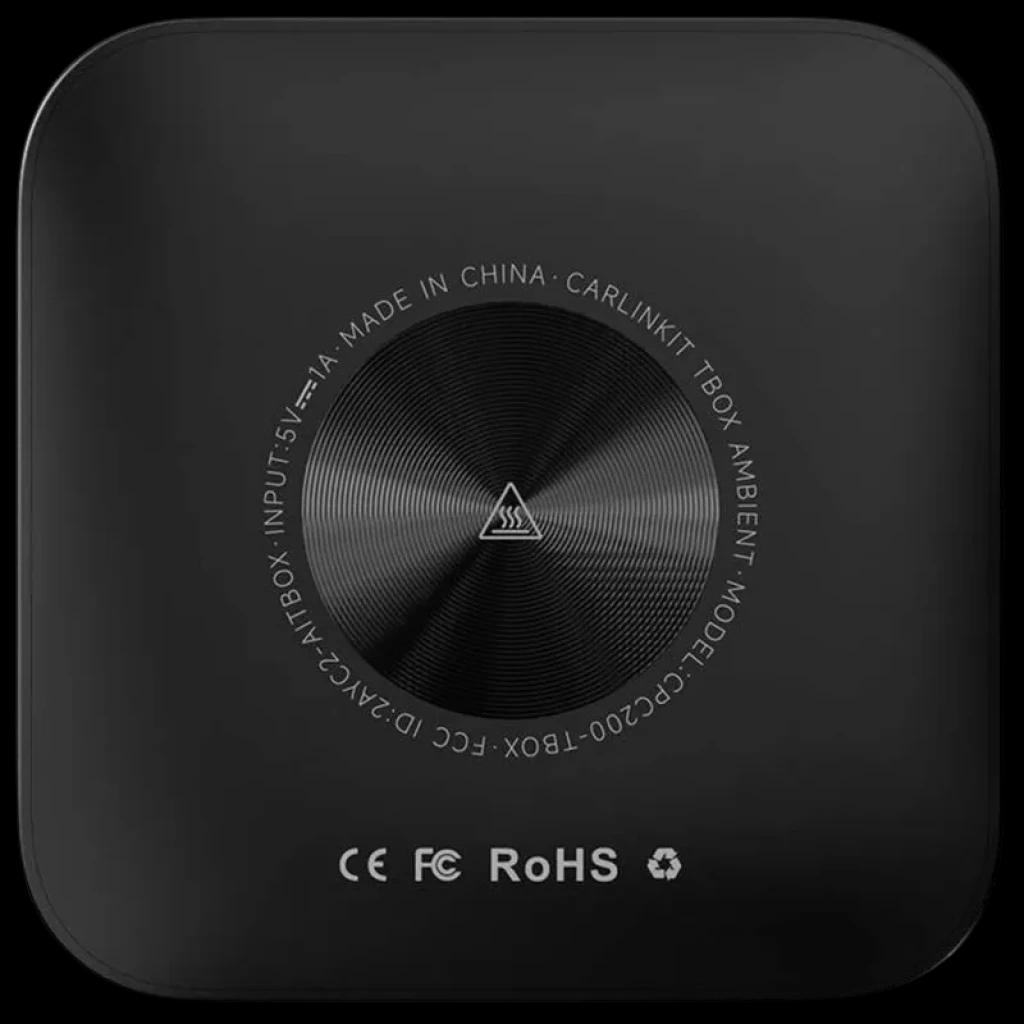 Carlinkit TBOX-Plus negro mate, caja compacta cuadrada con tapa lisa y anillo metálico central cepillado; certificaciones CE, FCC y RoHS visibles en la base