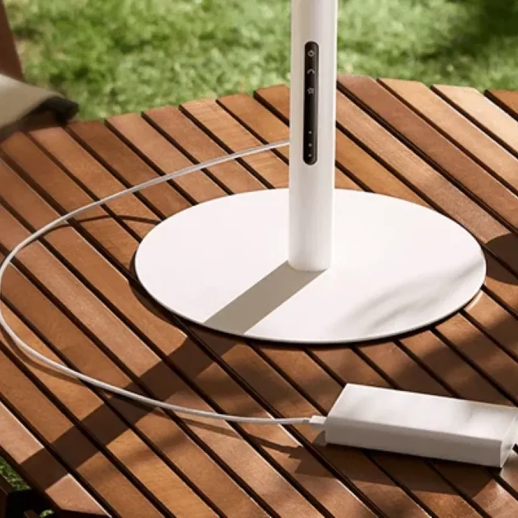 Base du Mijia Smart Standing Fan Pro Slim EU avec port USB-C, câble branché et commandes tactiles sur le pied, design blanc épuré sur table en bois