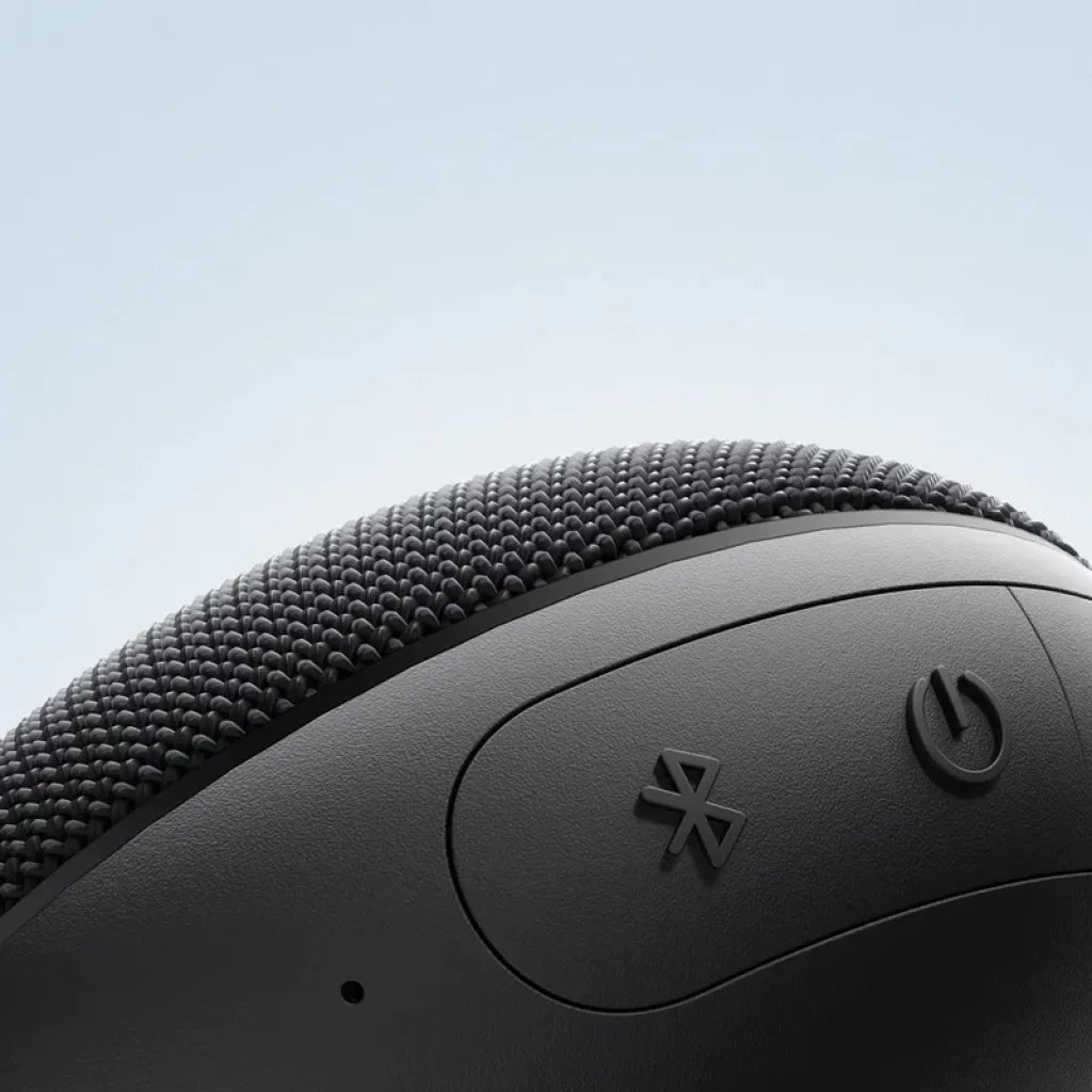 Xiaomi Bluetooth Speaker Essential 5W negro con textura de tela, botones de Bluetooth y encendido en relieve, diseño curvo compacto, resistencia IP66