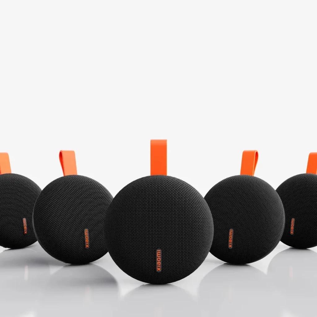 Altavoz portátil Xiaomi Bluetooth Speaker Essential 5W negro, diseño ovalado con malla textil, logo naranja y asa superior naranja, resistente IP66