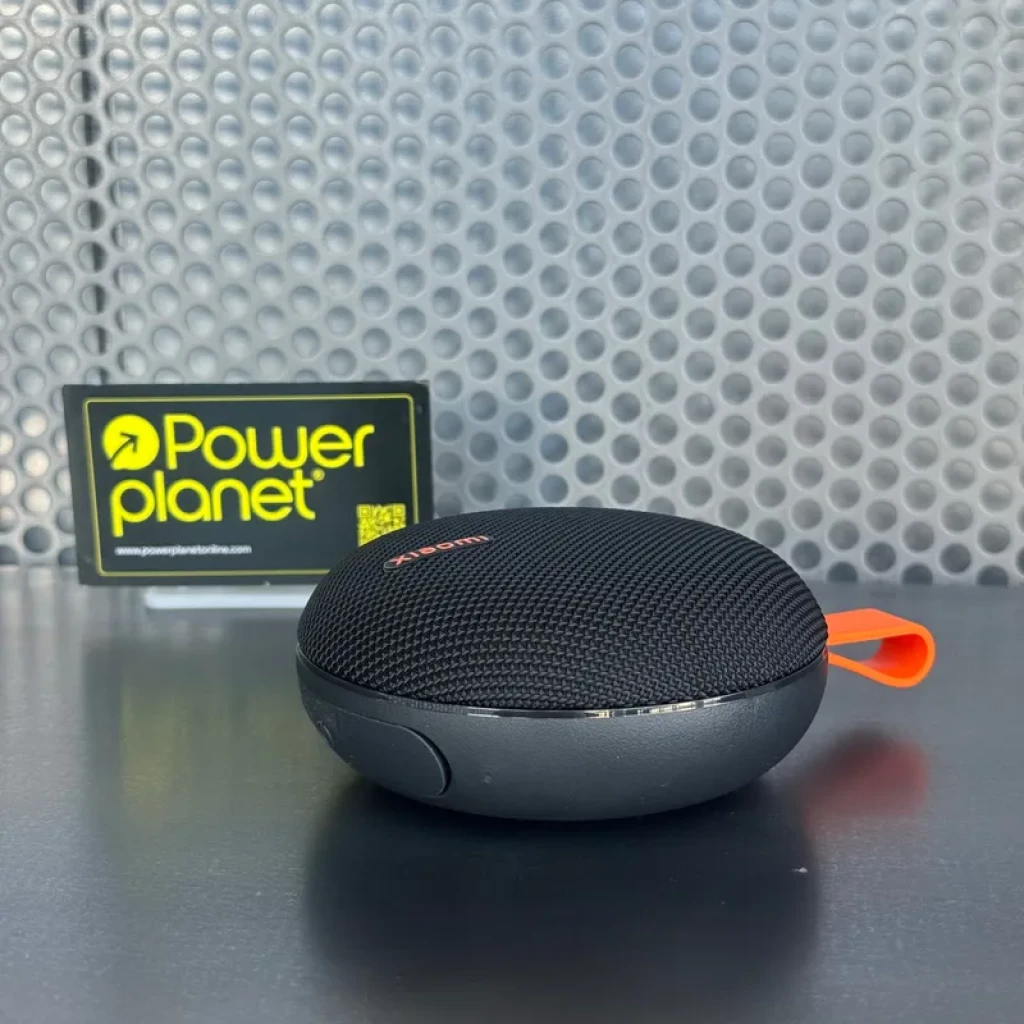 Xiaomi Bluetooth Speaker Essential 5W negro, compacto y redondo, rejilla textil, carcasa gris, lazo naranja para colgar, botón lateral, diseño resistente IP66