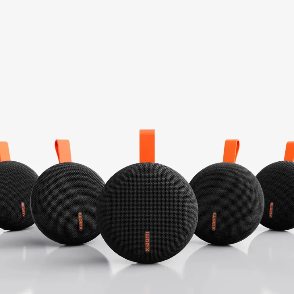 Altavoz portátil Xiaomi Bluetooth Speaker Essential 5W, color negro con asa naranja, diseño ovalado con rejilla textil y logotipo, compacto y resistente IP66