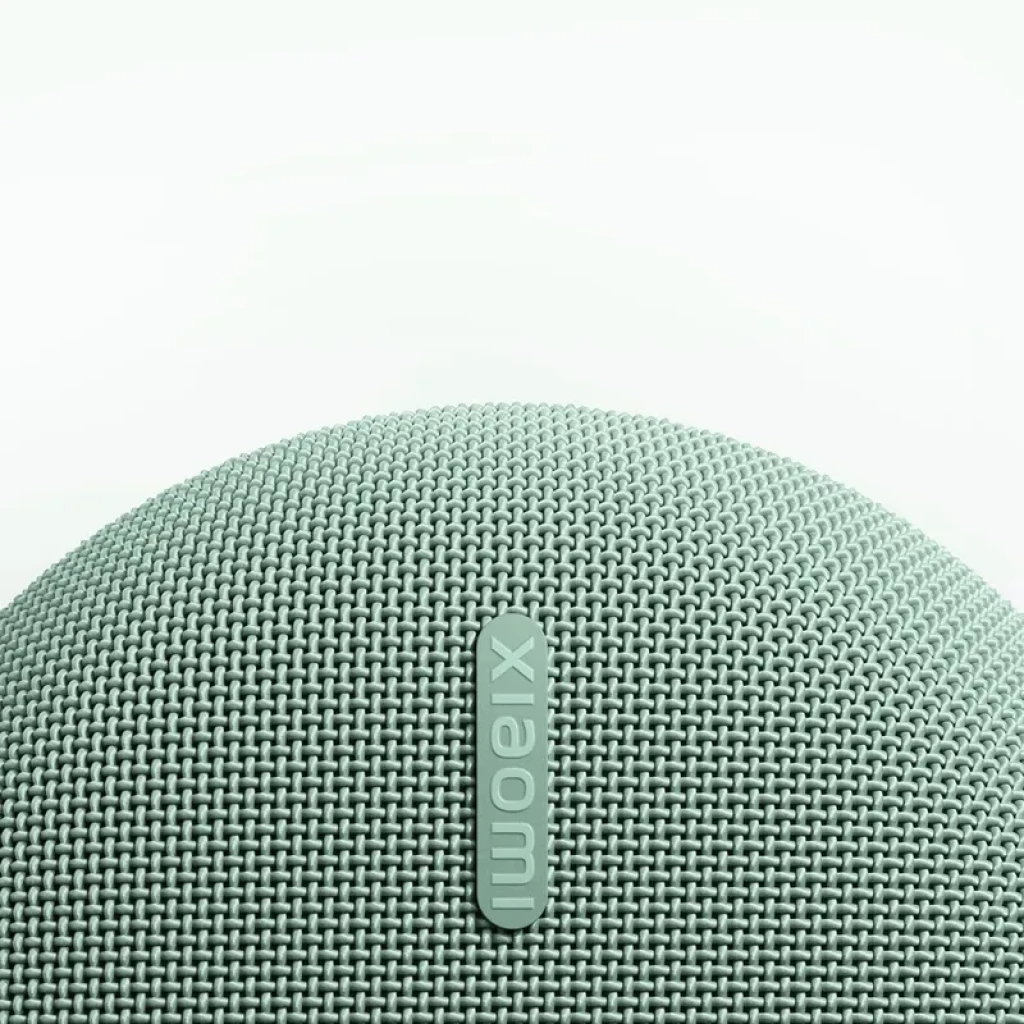 Altavoz portátil Xiaomi verde con rejilla textil curva y logo vertical en relieve; diseño compacto y moderno, acabado tejido en tono menta